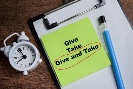 Concept of give and take in red circle write on sticky notes isolated on Wooden Table.の写真素材