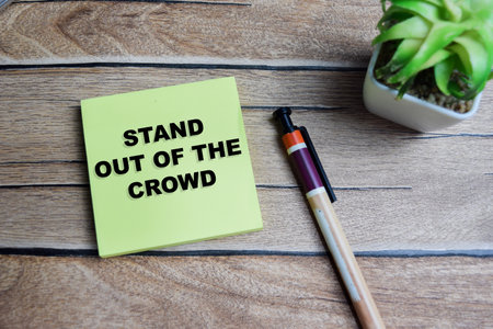 Concept of stay out of the crowd write on sticky notes isolated on Wooden Table.の写真素材