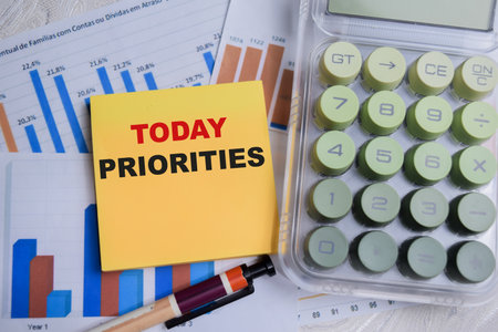 Concept of today priorities write on sticky notes with financial graphs isolated on Wooden Table.