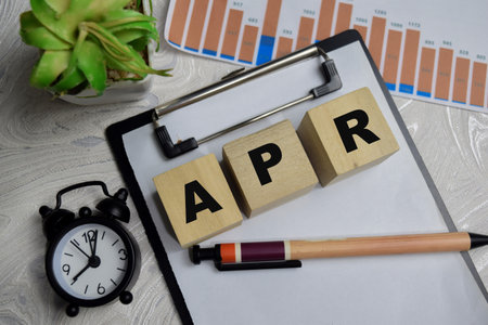 Annual Percentage Rate stacked wooden cubes with financial graphs on the table.の写真素材