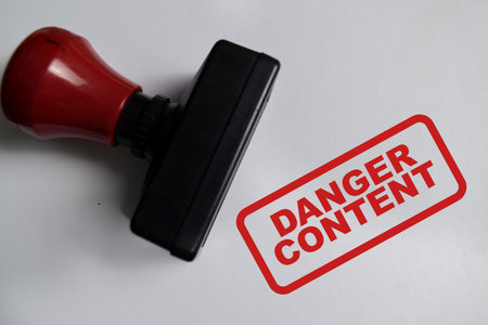 Red Handle Rubber Stamper and danger content text above book isolated on wooden backgroundの写真素材