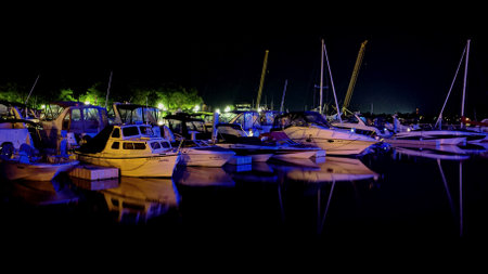 Boats docked at Peakes Wharf in Downtown Charlottetown, PEI on a midsummer night. The calm night allows the dark still Atlantic Ocean waters to draft the reflection of the boats.のeditorial素材