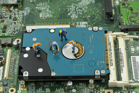 service maintainance of hard disk by mini worker team on mainboard background - can use to display...