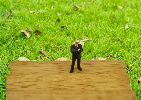 abstract mini businessman stand on wood block with green feilds background - can use to display or montage on productの写真素材