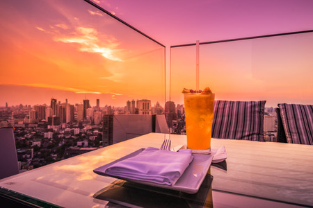 abstract yellow cocktail on rooftop bar and cityscape view with twilight sunset time - can use to display or montage on productの写真素材