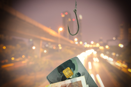 abstract phoshing concept with silver hook and credit card on urban cityscape backgroundの写真素材