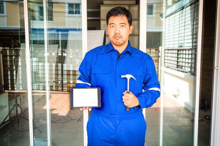 technician in blue suit hond hammber and tablet for house repair service