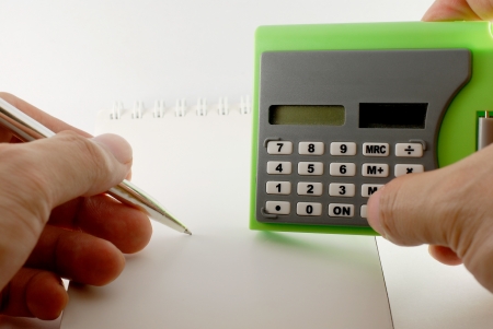 Hand hold calculator and pen with notebook on white backgroundの写真素材