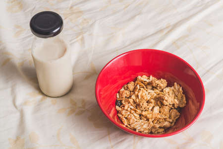Cereals in red bowl with milk bottle