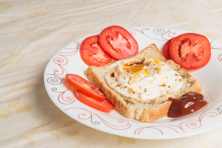 Eggs fired and sauce on bread with tomatoesの写真素材