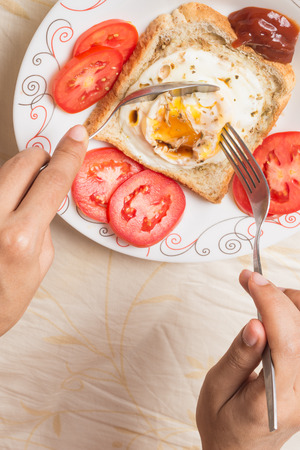 Hand scoop up eggs fired and sauce and tomatoe on breadの写真素材