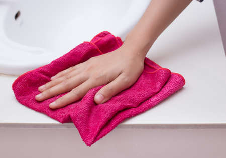 Hand with sponge cleaning white sink.の写真素材