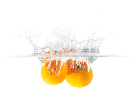 Fresh orange falling and splashing into water.の写真素材
