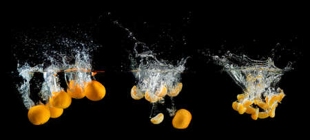 Fresh orange falling and splashing into water.の写真素材
