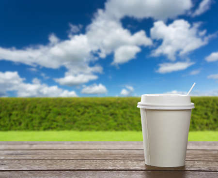 paper coffee cup on wooden table in gardenの写真素材