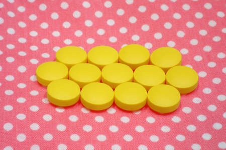 yellow tablets pills on pink background