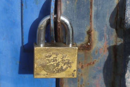 old padlock on blue alloy doorの写真素材