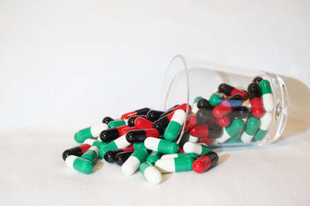 Red black and green white capsules in a little glassの写真素材
