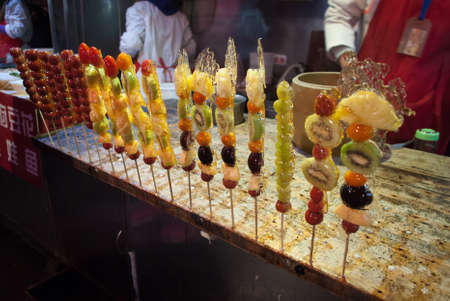 Sugar coating fruit skew at Wangfujing, Beijing. Tanghulu, also called bing tanghulu, is a traditional winter snack in northern China, especially in Beijing.の写真素材