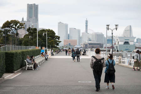 Yokohama, Japan - Mar 18, 2016 : Unidentified couple people walking along Yamashita park with Yokohama landmark building background.のeditorial素材
