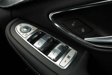 Car door interior armrest with window control panel, door lock button. Interior details.