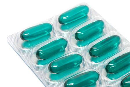 green soft gel capsules pills in blister pack isolated on white background.