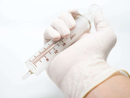 Old syringe medical equipment on hand with examination gloveの写真素材