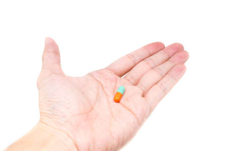 green orange color pills capsule on hand isolated on white backgroundの写真素材