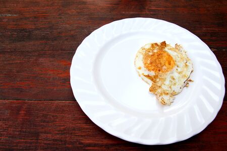 Fried egg on white dish on wooden table