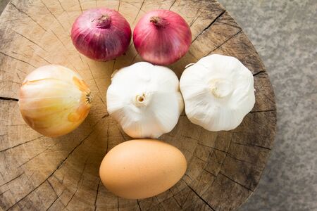 Raw garlic,onion,shallot,egg on cutting boardの写真素材