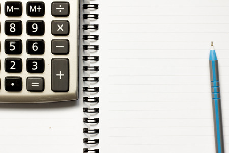 Blue pen and calculator placed on white paper backgroundの写真素材