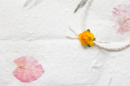 White mulberry paper with pink petal texture background and orange handmade flowerの写真素材