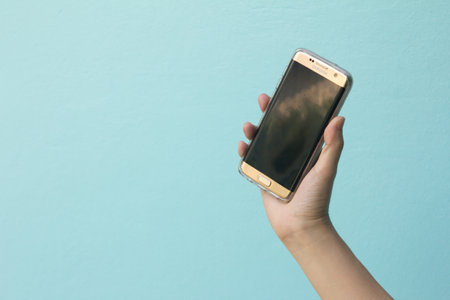 Bangkok, Thailand October 24, 2016 : Woman held android phone Samsung galaxy S7 Edge on blue concrete background.のeditorial素材