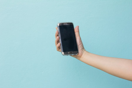 Bangkok, Thailand October 24, 2016 : Woman held android phone Samsung galaxy S7 Edge on blue concrete background.のeditorial素材