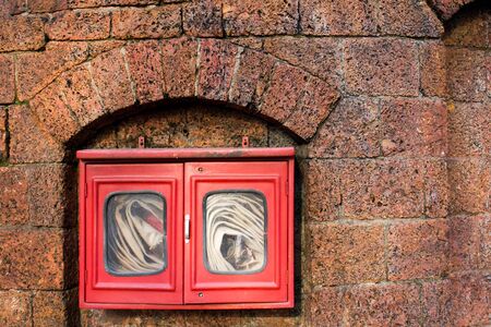 Fire hose in red box on brick wall backgroundの写真素材