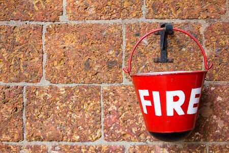 Red fire bin contain the sand on brick wall backgroundの写真素材
