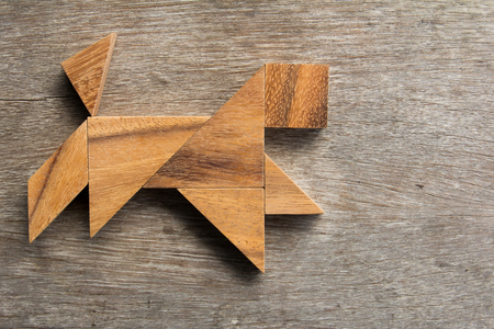 Wooden tangram as running dog shape on old wood backgroundの写真素材