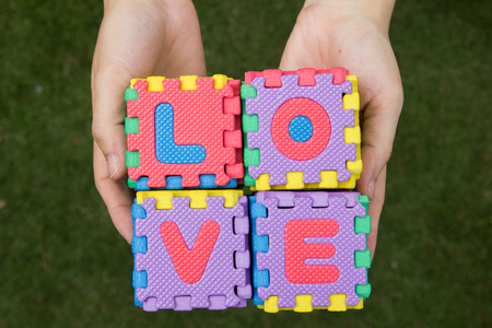 Puzzle wording love has hold on hand with green backgroundの写真素材