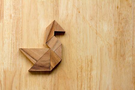 Tangram puzzle in swan shape on wooden backgroundの写真素材