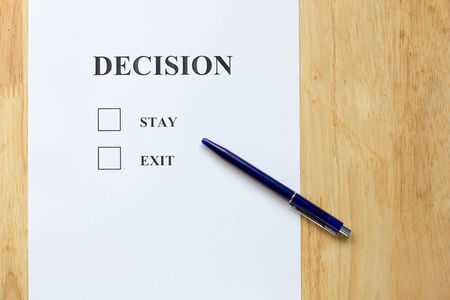 Decision paper with stay and exit choice on wood backgroundの写真素材