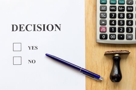 Decision paper with yes and no choice, pen, rubber stamp, calculator on wood background