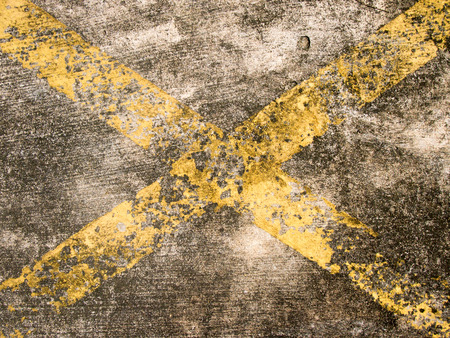 Grunge yellow line cross on stained concrete backgroundの写真素材