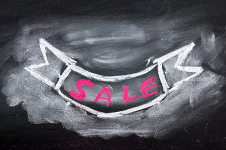 Grunge ribbon draw by white and red chalk with sale wording on black board backgroundの写真素材