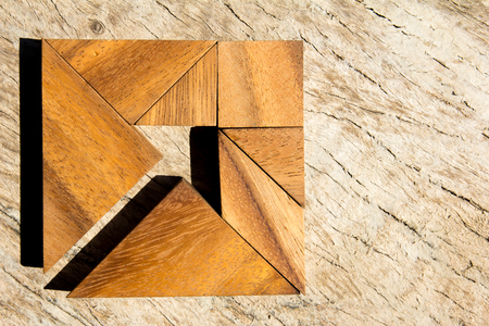 Tangram puzzle as arrow in square shape on wooden background (Concept for business direction and decision)の写真素材