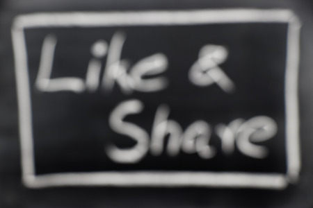 Blur Like & Share wording, hand writing by chalk on black board backgroundの写真素材