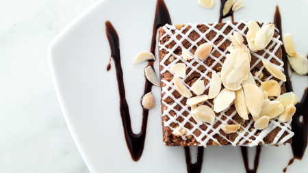 Top view of chocolate brownie with sliced almond on white plate backgroundの写真素材