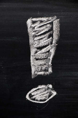 Exclamation mark draw by white chalk on black board backgroundの写真素材