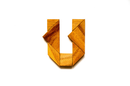 Wooden tangram puzzle as English alphabet letter "U" shape on white backgroundの写真素材