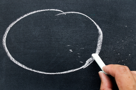 Man hold white chalk to write something on black board with circle background (Concept for business or education by have space to add text)の写真素材