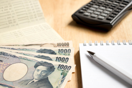 Bank passbook with japanese yen and book with pen, calculator on wood table backgroundの写真素材